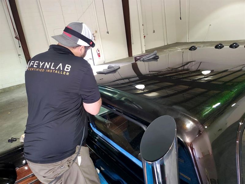 Slipstream Detailing owner Bryan Rose, a FEYNLAB Certified Installer, polishing a glossy black truck in the Frisco TX studio